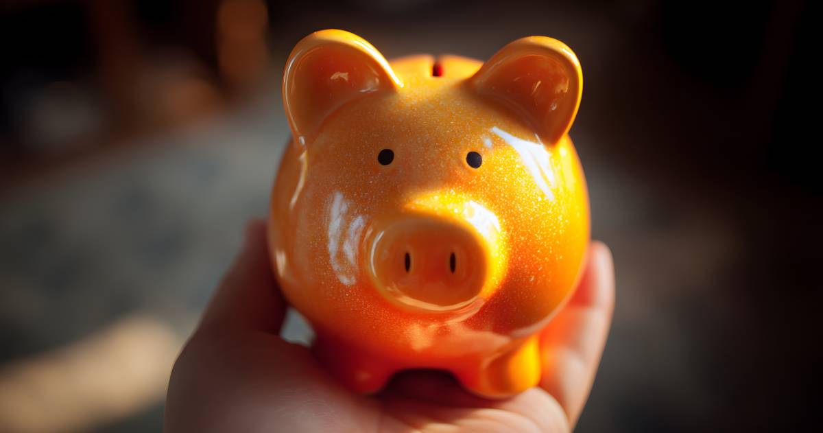 een rood oranje spaarvarken dat in een hand staat